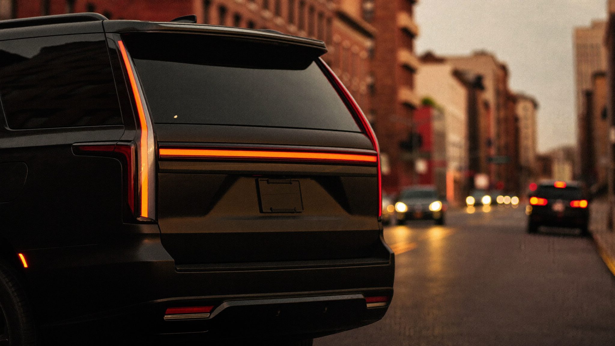 A private car waiting on a city street at dusk