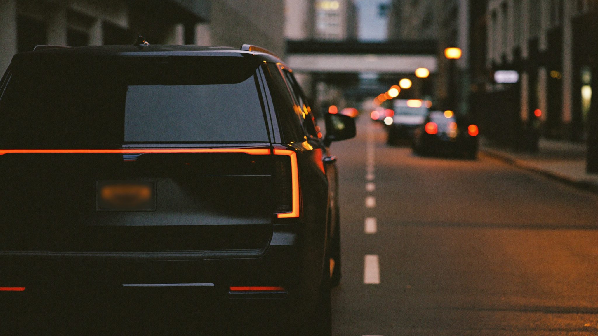 A black SUV pulling into a city street at dusk